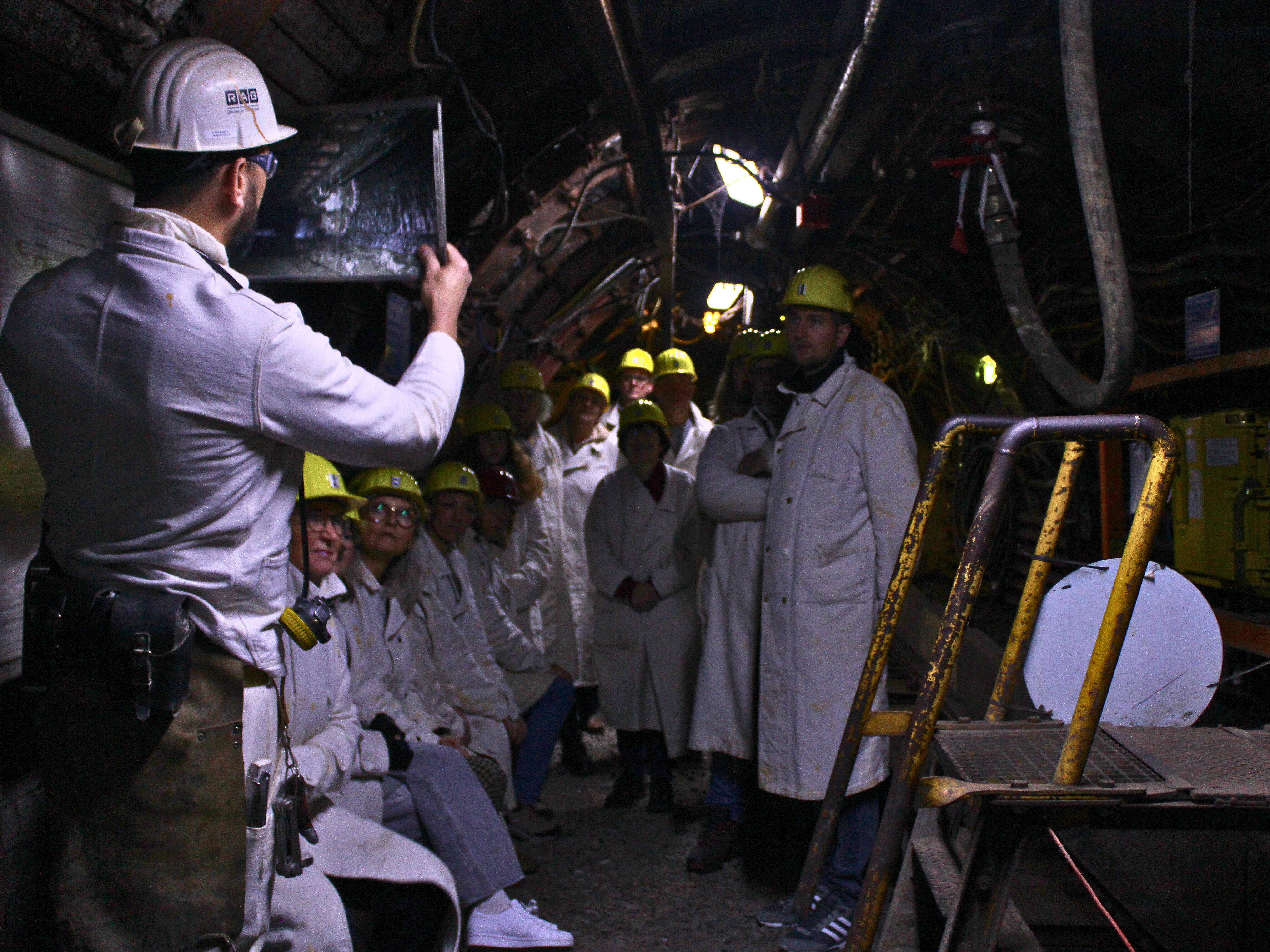 Pütt & Panorama -Tour im Trainingsbergwerk Recklinghausen Ein Guide hält im Trainingsbergwerk Recklingshausen ein Bild vor einer Gruppe Menschen hoch.