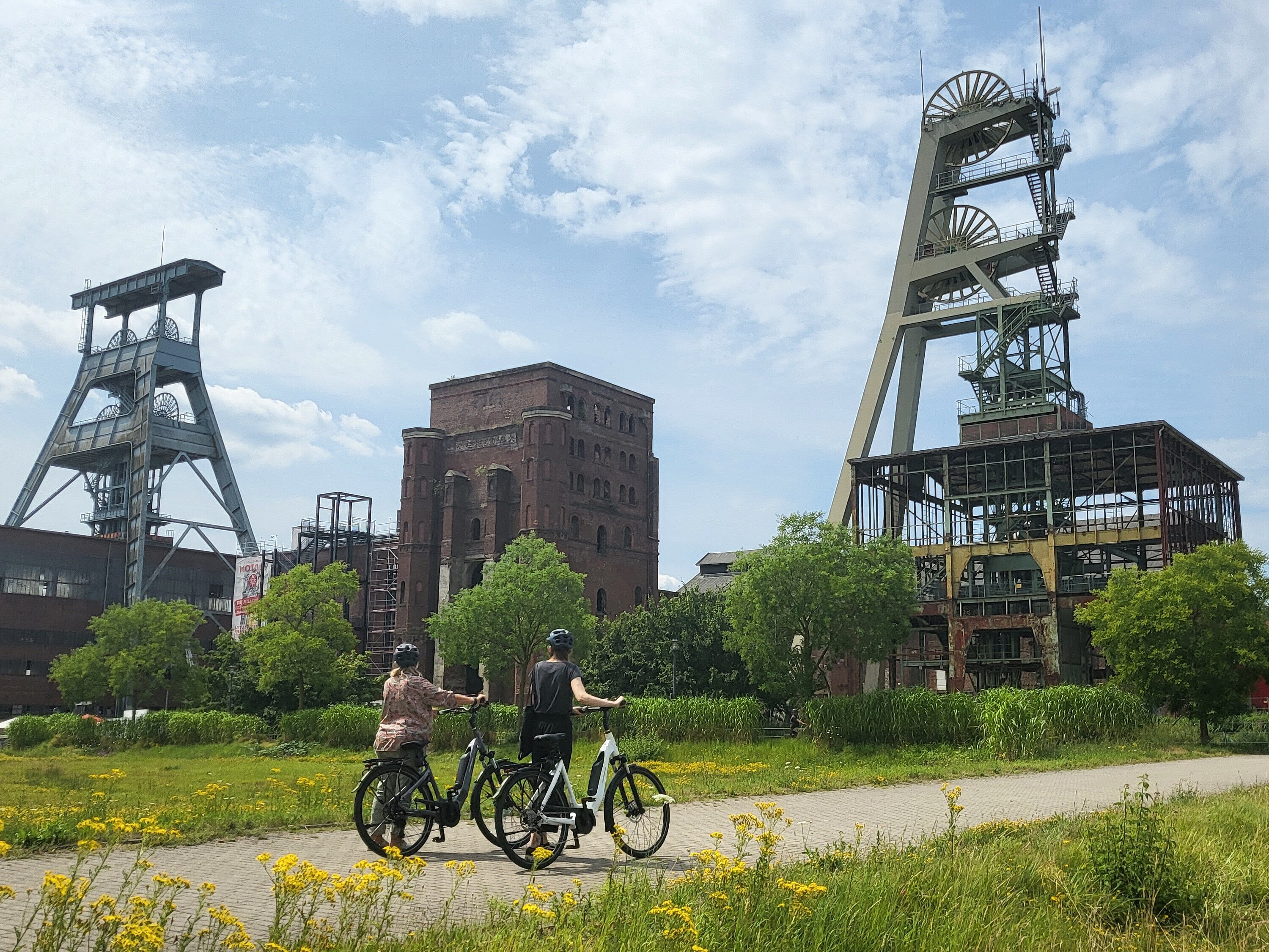 Radtour_Zeche_Ewald_RVR_Alina_Guss Zwei Personen fahren mit dem Fahrrad über das Gelände der ehemaligen Zeche Ewald.
