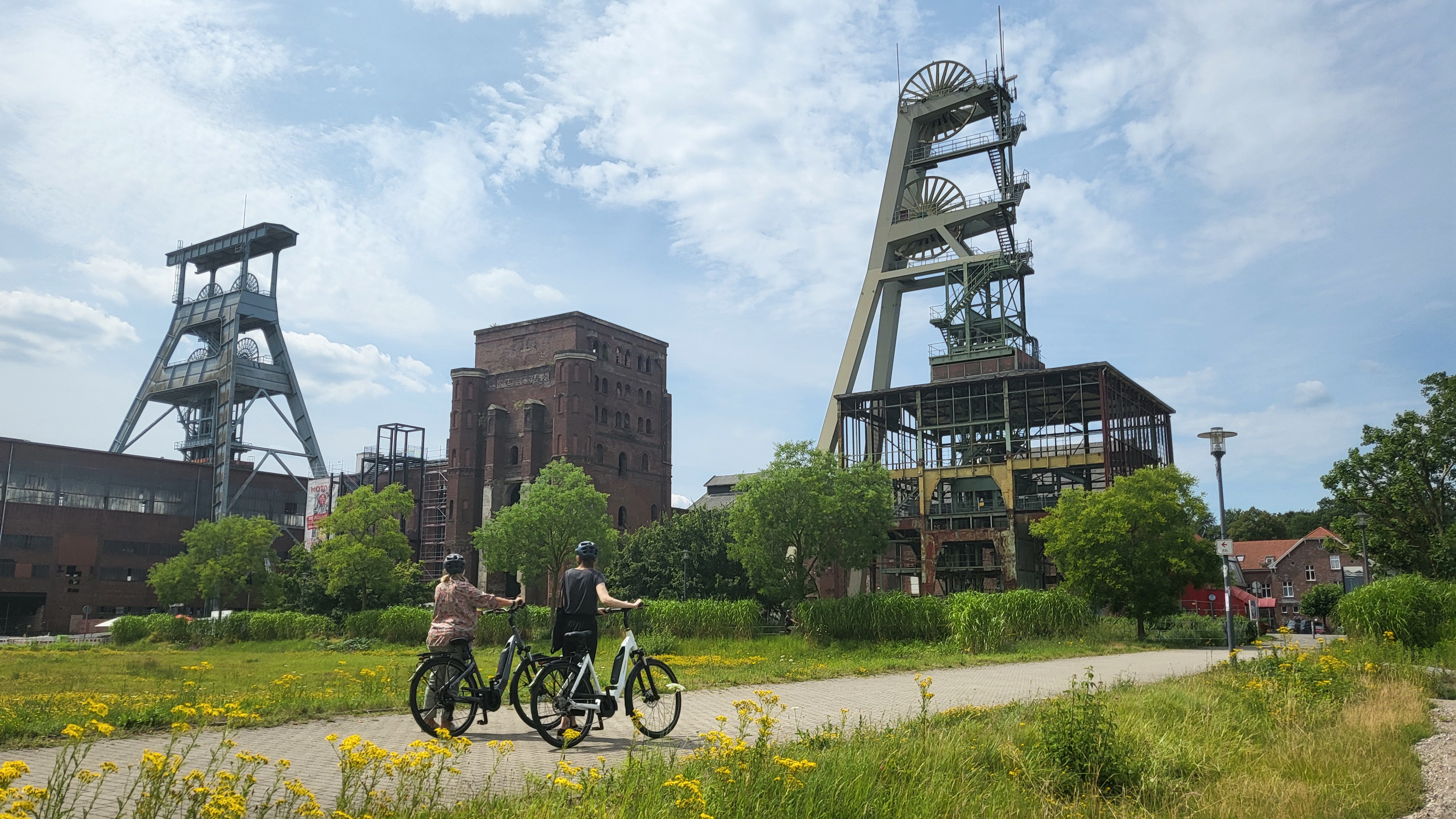 Radtour_Zeche_Ewald_RVR_Alina_Guss Zwei Personen fahren mit dem Fahrrad über das Gelände der ehemaligen Zeche Ewald.